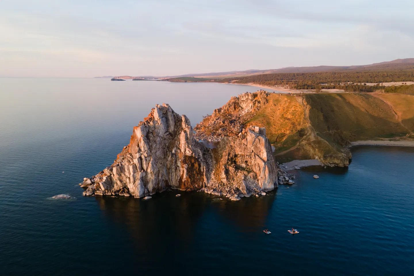 Shaman Rock and the shores of Olkhon Island rise from the calm blue waters of Lake Baikal