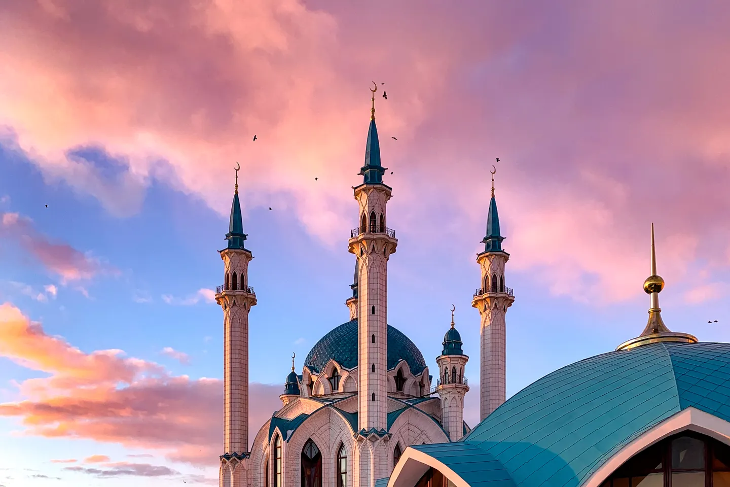 The turquoise domes and slender minarets of Kul Sharif Mosque beneath a pink evening sky in Kazan