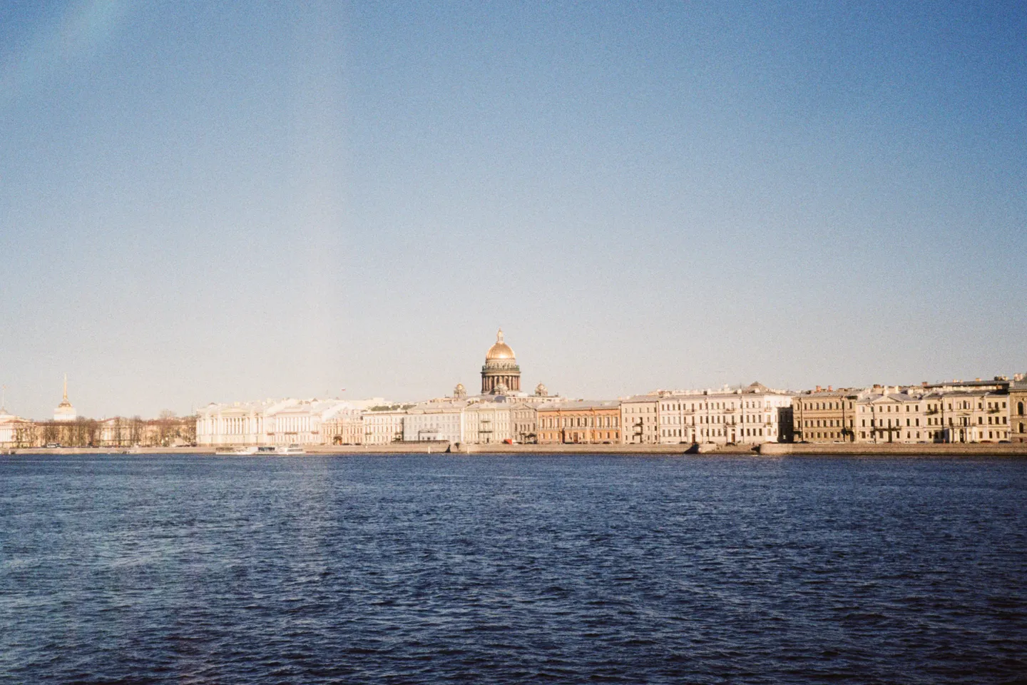 Saint Isaac’s golden dome rises above the pastel waterfront and the Neva River in Saint Petersburg